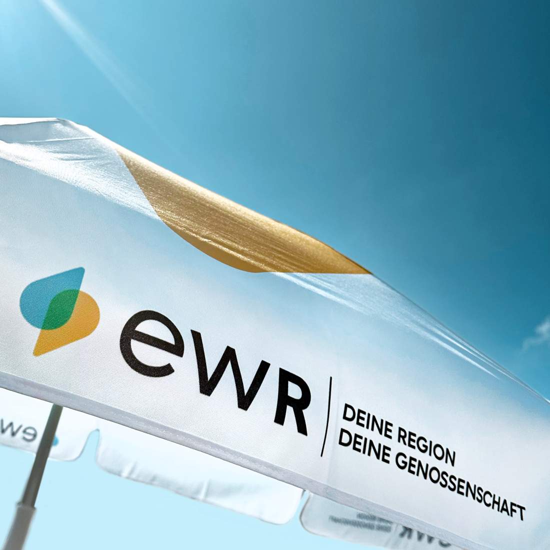 Ein Sonnenschirm im neuen Corporate Design des EWR.